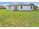 View of the house's backyard with a white exterior, sliding glass door, and ample green space at 16837 Sw 47Th Court Rd Rd, Ocala, FL 34473