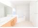 Bright bathroom featuring a double sink vanity, large mirror, soaking tub, and neutral tile flooring at 2110 Korat Ln, Maitland, FL 32751