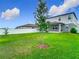 Expansive backyard with a young tree, green lawn, and a view of the home's exterior, perfect for outdoor enjoyment at 2279 Raven Ridge Road, Minneola, FL 34715