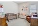 Bright bedroom with a crib, sitting chair, and floral wall decor at 2279 Raven Ridge Road, Minneola, FL 34715