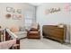 Cozy bedroom with a crib, comfy chair, and charming 'Lilah' wall art at 2279 Raven Ridge Road, Minneola, FL 34715