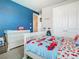 This charming bedroom features fun décor, a blue accent wall, and ample closet space at 2279 Raven Ridge Road, Minneola, FL 34715
