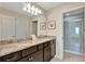 Bathroom featuring double sinks with granite countertop, dark cabinets and glass-enclosed shower at 2408 Dubai St, Kissimmee, FL 34747