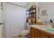 Bathroom with shower curtain, wood vanity and an open metal shelving unit at 3037 Diamond Ln, St Cloud, FL 34772