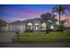 Charming single-story home with a well-manicured lawn, arched windows, and a two car garage at dusk at 3037 Diamond Ln, St Cloud, FL 34772
