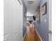 Long hallway leads to a home office and features wood floors, blue walls, and decorative art at 3037 Diamond Ln, St Cloud, FL 34772