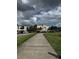 Sidewalk leading to condos and covered parking with blue skies and green space on either side at 3321 Whitestone Cir # 204, Kissimmee, FL 34741
