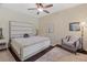 Comfortable bedroom featuring neutral walls, ceiling fan, upholstered bed frame, side tables and a comfy chair at 3535 Clay Brick Rd, Harmony, FL 34773