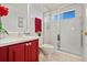 Clean bathroom featuring a glass shower, red vanity, and neutral colored tiles at 615 Copeland Dr, Haines City, FL 33844