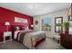 Comfortable bedroom with red accent wall, plush carpet and bright window at 615 Copeland Dr, Haines City, FL 33844