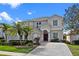 Stucco two-story home with well-manicured landscaping, palm trees, and a red front door at 615 Copeland Dr, Haines City, FL 33844