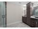 Bathroom with dark cabinets, stone sink, granite countertops, and glass shower at 6873 Slaven Dr, Orlando, FL 32819