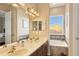 Bright bathroom with a double sink vanity, large mirror, and separate bathtub area by the window at 7422 Sparkling Ct, Reunion, FL 34747