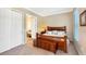 Well-lit bedroom with neutral walls, wood furniture, carpet flooring, and a doorway to the bathroom at 7422 Sparkling Ct, Reunion, FL 34747