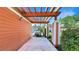 View of the carport, with an orange wood pergola and car parked under it, and orange walls at 7422 Sparkling Ct, Reunion, FL 34747