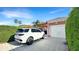 View of the driveway and garage of an orange home with a black and white SUV at 7422 Sparkling Ct, Reunion, FL 34747