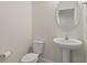 Compact powder room with a pedestal sink, toilet, and round mirror at 8724 Peachtree Park Ct, Windermere, FL 34786