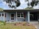Close up of charming one-story home with covered entry and red shutters at 921 Louisiana Ave, St Cloud, FL 34769
