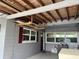 Enclosed porch featuring exposed ceiling beams and gray wood paneled walls, perfect for storage and projects at 921 Louisiana Ave, St Cloud, FL 34769