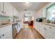 A kitchen featuring white cabinets, wood-look flooring, stainless steel appliances and a view to the living room at 1422 Missouri Ave, St Cloud, FL 34769