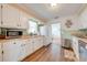 A kitchen featuring white cabinets, wood-look flooring, a microwave and a stainless steel dishwasher at 1422 Missouri Ave, St Cloud, FL 34769