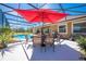 Outdoor dining by the screened-in pool area with a large umbrella at 1941 Mathis Rd, St Cloud, FL 34771