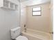 This bathroom has a tiled shower-tub combination and toilet with a window for natural light at 218 Cranbrook Dr, Kissimmee, FL 34758