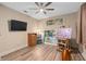 Bedroom with light wood floors, a ceiling fan, TV, window, an easel with painting, and various other paintings at 2234 Callaway Ct, Davenport, FL 33837