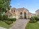 Elegant two-story home with a tile roof, arched windows, and a paver driveway at 2234 Callaway Ct, Davenport, FL 33837