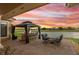 Outdoor patio with a gazebo, dining table, and wet bar overlooking a calm lake at sunset at 2234 Callaway Ct, Davenport, FL 33837