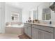 Bright bathroom featuring double sink vanity with gray cabinetry and a garden tub at 2877 Fitness St, Clermont, FL 34714