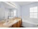 Bathroom with double sinks, wood cabinets, and a tub/shower combo adjacent to a soaking tub under a window at 4125 Navigator Way, Kissimmee, FL 34746