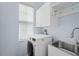 Laundry room with a white washer and dryer, white cabinets, and a stainless steel sink at 4125 Navigator Way, Kissimmee, FL 34746