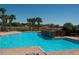 Community pool with palm trees, lounge chairs, water features and umbrellas on a sunny day at 4525 Sw 52Nd Cir # 103, Ocala, FL 34474