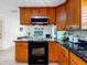 Kitchen with black appliances, wood cabinets, granite countertop, hardwood floors with a view of the living room at 5123 Lighthouse Rd, Orlando, FL 32808