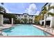 Inviting community pool surrounded by swaying palm trees and comfortable lounge chairs at 5550 E Michigan St # 2214, Orlando, FL 32822