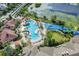 Aerial view of a resort-style pool area with water slides, surrounded by palm trees and lush landscaping near a lake at 7719 Comrow St, Kissimmee, FL 34747