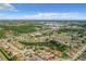 A sprawling aerial view capturing a residential neighborhood with many mature trees and commercial buildings at 832 Whalebone Bay Dr, Kissimmee, FL 34741