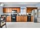 Well-equipped kitchen featuring wood cabinetry, black appliances, granite countertops, and tile flooring at 932 Emerald Green Ct, Kissimmee, FL 34746