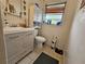 Functional bathroom featuring a modern vanity, a toilet with upper cabinet, and a window with wood blinds at 1617 Emmett St, Kissimmee, FL 34741