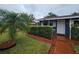 Charming single-story home boasts a well-manicured front yard with lush green landscaping, shrubs and palm tree at 1617 Emmett St, Kissimmee, FL 34741