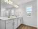 Bathroom with double sink vanity, wood-look tile flooring, and decorative light fixtures at 1650 Sugarbelle Cir, Mascotte, FL 34753