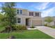 Attractive two-story home with a well-maintained lawn, an attached garage, and a welcoming front entrance at 1650 Sugarbelle Cir, Mascotte, FL 34753