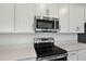 Close-up highlighting stainless steel oven, microwave, white cabinets, and countertops in a modern kitchen at 1650 Sugarbelle Cir, Mascotte, FL 34753