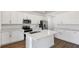 Bright kitchen showcasing white cabinets, stainless steel appliances, a central island, and wood-look flooring at 1650 Sugarbelle Cir, Mascotte, FL 34753