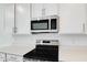 Close-up showcasing the stainless steel microwave and range with a black cooktop, complemented by quartz countertops at 1690 Sugarbelle Cir, Mascotte, FL 34753