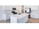 Modern kitchen with white cabinets, quartz countertops, stainless steel appliances, and a large island at 1690 Sugarbelle Cir, Mascotte, FL 34753