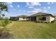 Spacious backyard with lush green lawn, mature landscaping, and a screened lanai at 204 Bella Cortina Dr, Poinciana, FL 34759