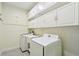 Bright laundry room featuring a washer, dryer, sink and ample storage in white cabinets at 204 Bella Cortina Dr, Poinciana, FL 34759