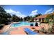 Community pool with lounge chairs under a blue sky surrounded by trees and an adjacent building at 4871 Coral Castle Dr, Kissimmee, FL 34746